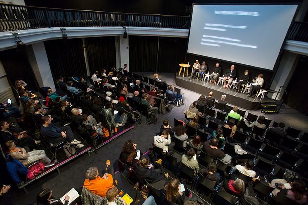 Ein Podiumsdiskussion im silent green Kulturquartier, fotografiert von oben herab auf den gefüllten Veranstaltungssaal, auf einer Bühne sitzen sechs Personen.