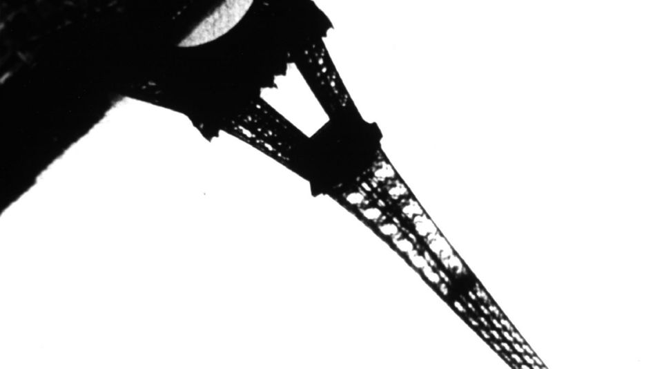 Film still from JEUX DES REFLETS ET DE VITESSE: A black-and-white photograph of the Eiffel Tower, which extends diagonally from the top left to the bottom right of the image.