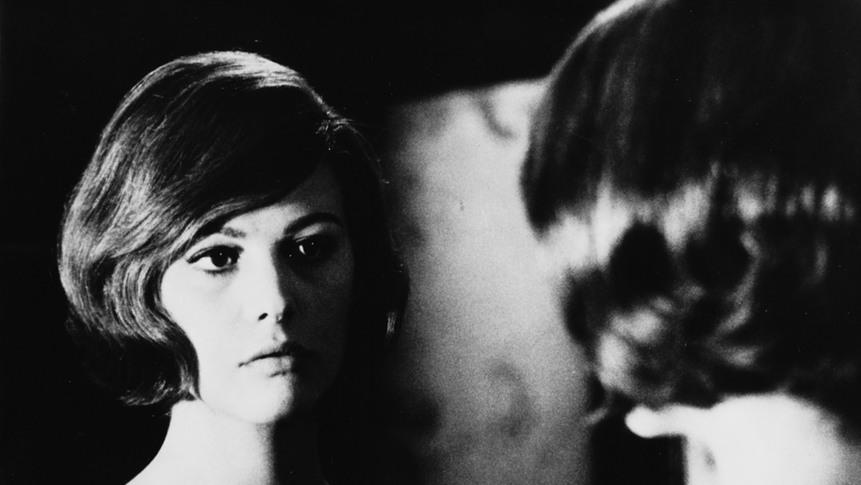 Film still from GLI INDIFFERENTI: A woman looks at herself in the mirror.