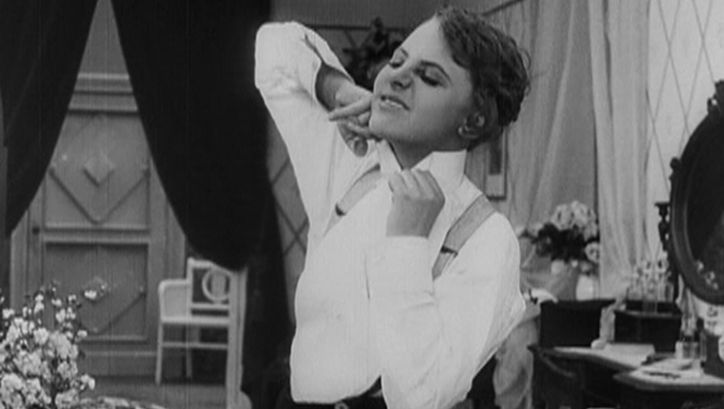 Filmstill aus ICH MÖCHTE KEIN MANN SEIN. Eine junge Frau kämpft mit ihrem Hemdkragen.