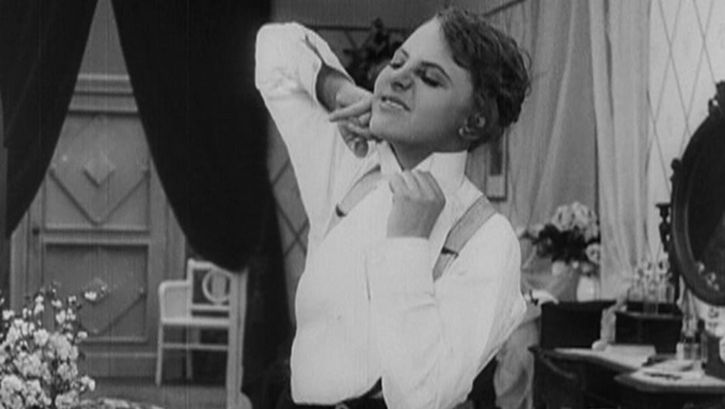 Film still from ICH MÖCHTE KEIN MANN SEIN. A young woman struggles with her shirt collar.