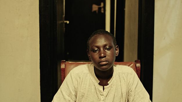 Filmstill from „The Bride" by Myriam U. Birara. A woman sitting on a chair stares into space.