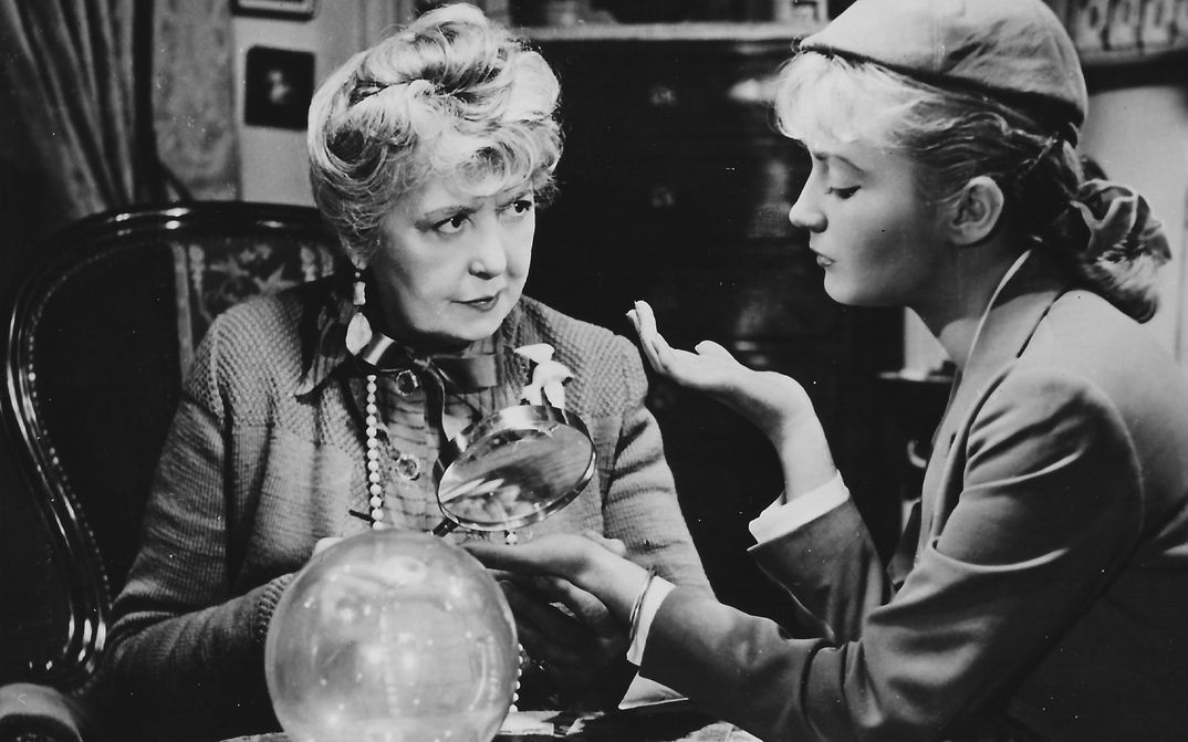 Filmstill aus SOUS LE CIEL DE PARIS COULE LA SEINE: Eine ältere und eine jüngere Frau sitzen gemeinsam an einem Tisch.