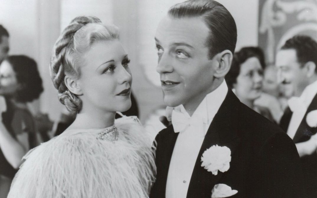 Film still from TOP HAT. Ginger Rogers and Fred Astaire in festive attire at a ball.