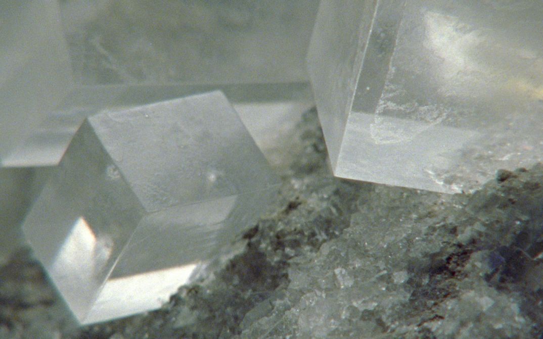 Film still from Deborah Stratman’s „Last Things“. Three big clear cuboid crystals on the upper half of the image on the base of small, almost equally clear crystals on the bottom half.