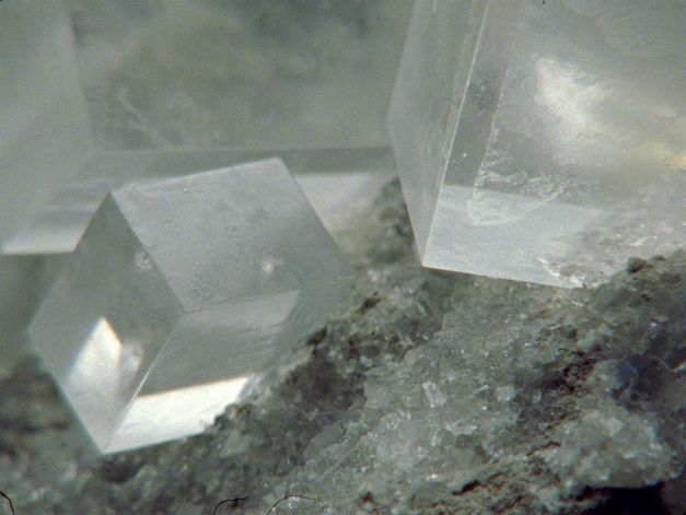 Film still from Deborah Stratman’s „Last Things“. Three big clear cuboid crystals on the upper half of the image on the base of small, almost equally clear crystals on the bottom half.