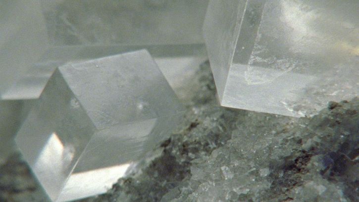 Filmstill aus dem Film „Last Things“ von Deborah Stratman. Drei große quaderförmige klare Kristalle in der oberen Bildhälfte auf einer Basis aus ähnlich klaren kleinen Kristallen in der unteren Bildhälfte.