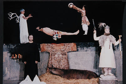 Filmstill aus SAJAT NOVA: Ein surrealistisches Tableau mit mehreren Figuren vor einem dunklen Hintergrund.