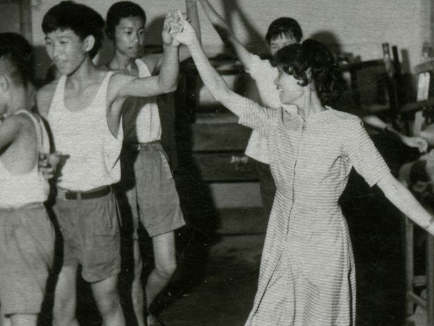 Film still from Lei Lei’s “That Day, on the River“. Black and white image of a group of people dancing.