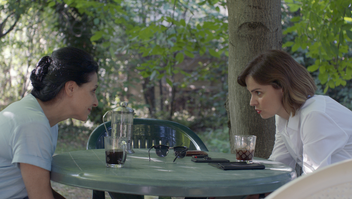 Filmstill aus COMETS. Zwei Frauen blicken sich über einen Tisch hinweg an.