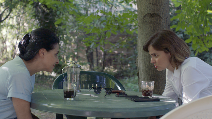 Filmstill aus COMETS. Zwei Frauen blicken sich über einen Tisch hinweg an.