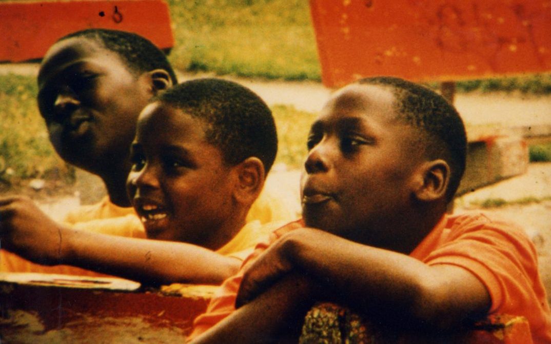 Film still from PUBLIC HOUSING. Three boys are looking at something off screen.