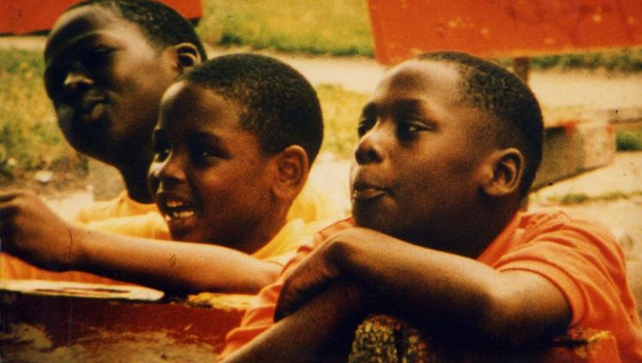 Filmstill aus PUBLIC HOUSING. Drei Jungs betrachten etwas im Off des Bildes.