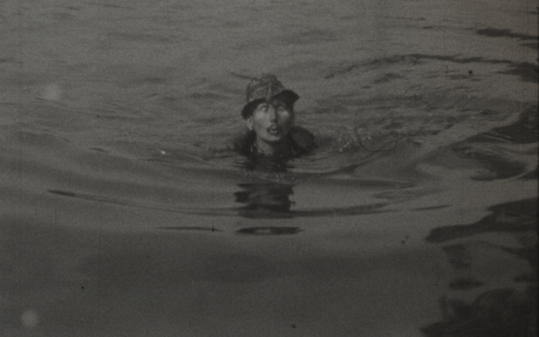 Filmstill aus HASTRMAN: Ein Mann mit Hut schwimmt in in einem Gewässer.