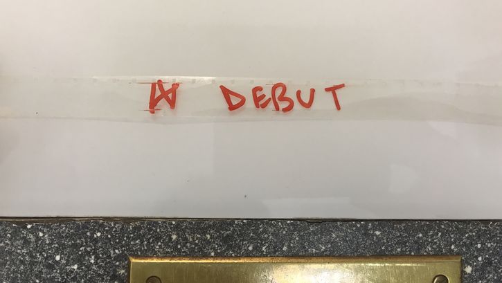 Auf einen transparenten Filmstreifen ist das Wort "Debut" mit rotem Filzstift geschrieben.