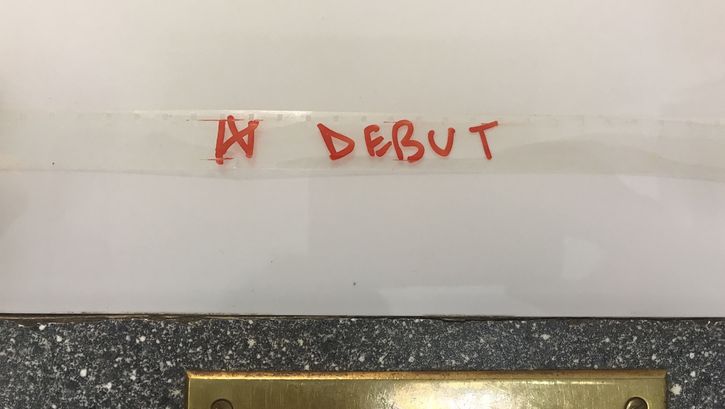 The word "Debut" is written in red felt-tip pen on a transparent film strip.
