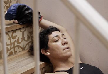 Still from the film "La edad media (The Middle Ages)" by Alejo Moguillansky and Luciana Acuña. A woman lays on stairs with her eyes closed. Her arm is above her head, and she is wearing a boxing glove