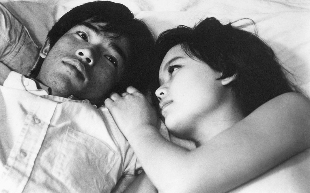 Film still from NANAMI, THE INFERNO OF FIRST LOVE: Two young people lie next to each other in bed. 
