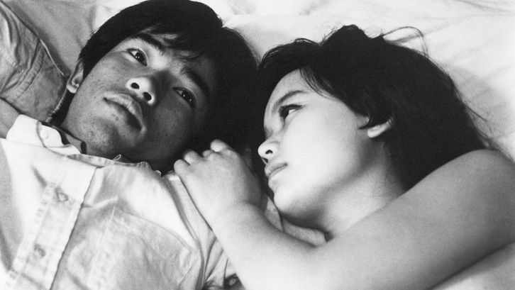 Film still from NANAMI, THE INFERNO OF FIRST LOVE: Two young people lie next to each other in bed. 
