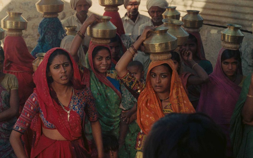 Filmstill aus MANTHAN: Einige Frauen in bunten Saris tragen Gefässe auf dem Kopf.