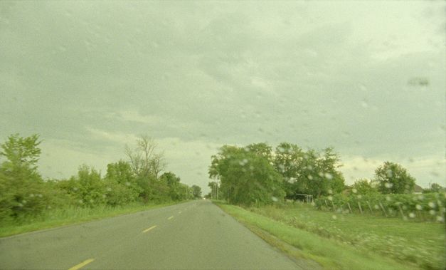 Still from the film "Akyn (Poet)" by Darezhan Omirbayev. We see an empty road through a rainy windshield.