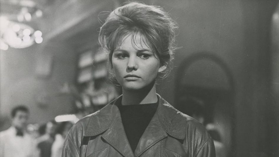 Film still from I DELFINI: Close-up of a young woman standing in a restaurant.
