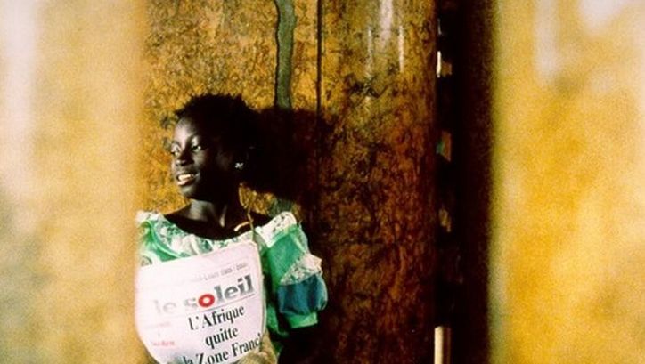 Filmstill aus LA PETITE VENDEUSE DE SOLEIL: Ein Mädchen steht mit einer Ausgabe der Zeitung "Le Soleil" an einer Ecke.