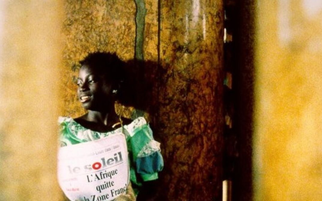 Filmstill aus LA PETITE VENDEUSE DE SOLEIL: Ein Mädchen steht mit einer Ausgabe der Zeitung "Le Soleil" an einer Ecke.