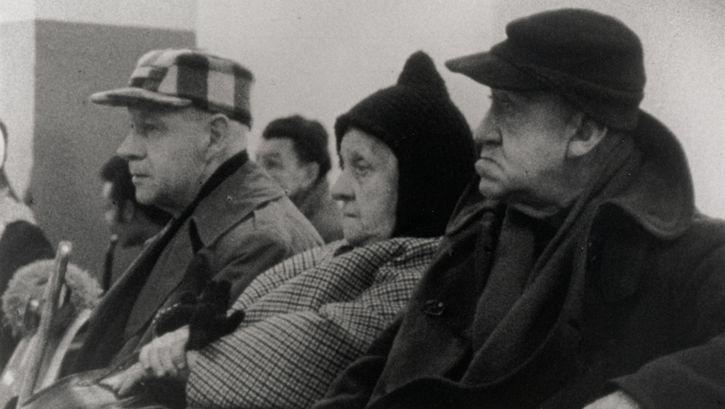 Film still from WELFARE. Three elderly people are sitting in a waiting room.