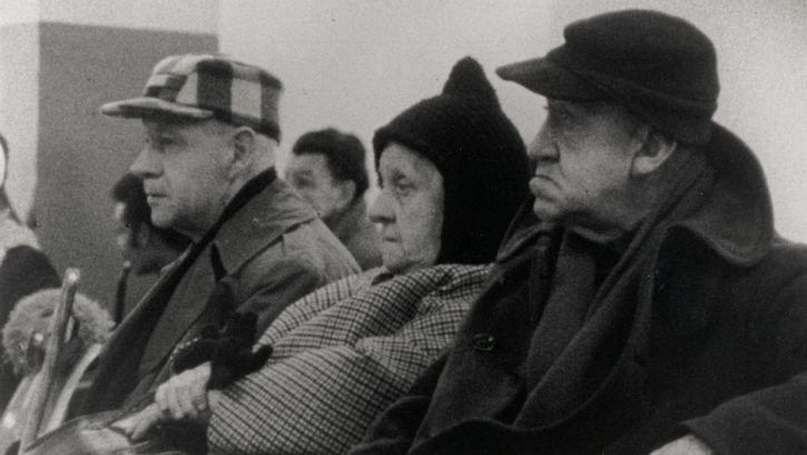 Film still from WELFARE. Three elderly people are sitting in a waiting room.