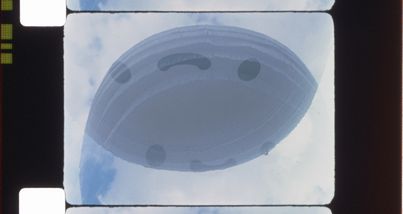 Ein Filmstreifen mit der Perforation ist zu sehen. Auf dem Bild ist ein ovales Objekt im Himmel zu sehen.