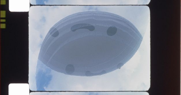 Ein Filmstreifen mit der Perforation ist zu sehen. Auf dem Bild ist ein ovales Objekt im Himmel zu sehen.