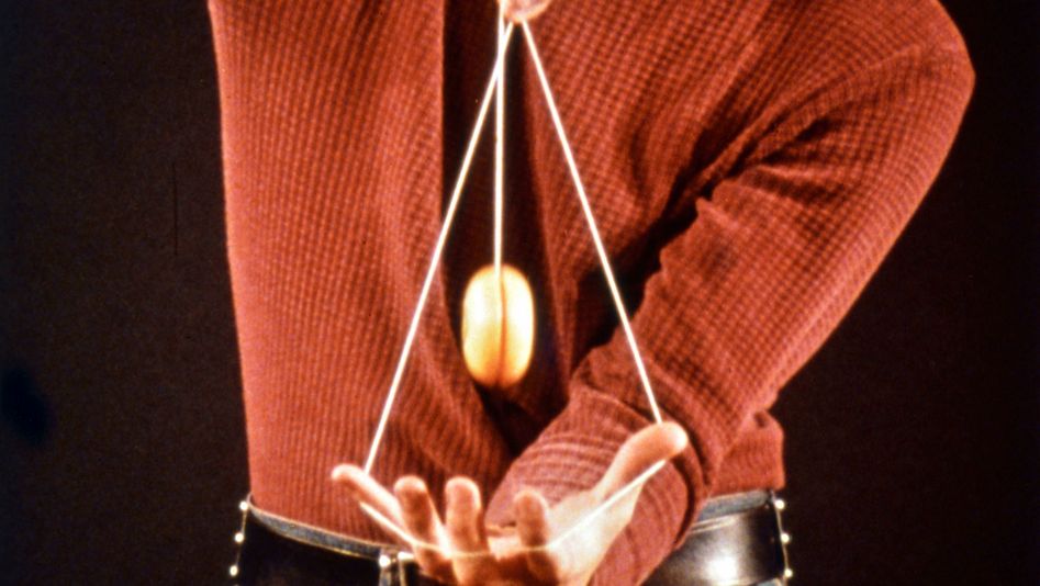 Filmstill aus 33 YO-YO TRICKS. Man sieht den Oberkörper und die Hände einer Person, die mit einem Yo-Yo spielt.