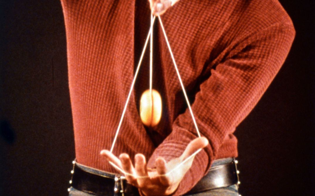 Film still from 33 YO-YO TRICKS. You can see the upper body and hands of a person playing with a yo-yo.