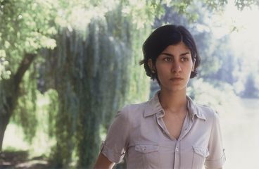 Filmstill aus „Der schöne Tag“ von Thomas Arslan. Eine junge Frau in Nahaufnahme geht durch einen Park. 