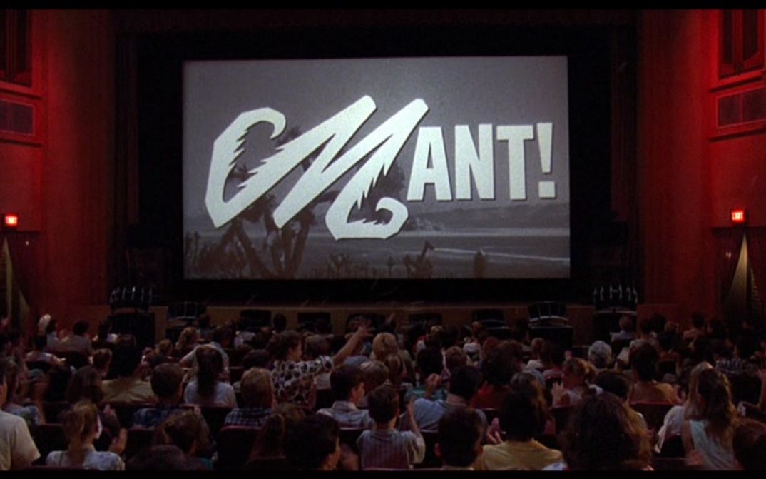 Filmstill aus MATINEE: Man sieht einen vollbesetzten Kinosaal, auf der Leinwand wird ein schwarz-weiß-Film gezeigt.