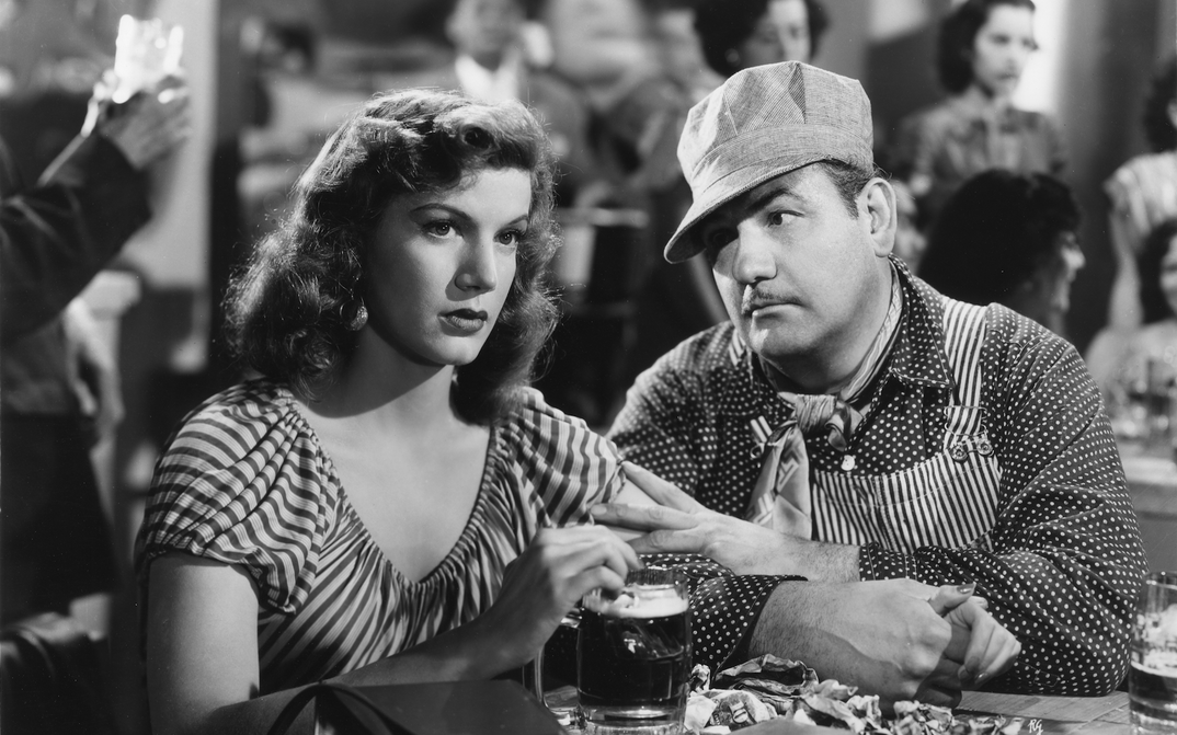 Film still from TROTACALLES: A man and a woman are sitting at a pub table.