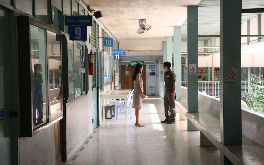 Film still from SYNDROMES AND A CENTURY: A woman and a man are standing in the hallway of a hospital.