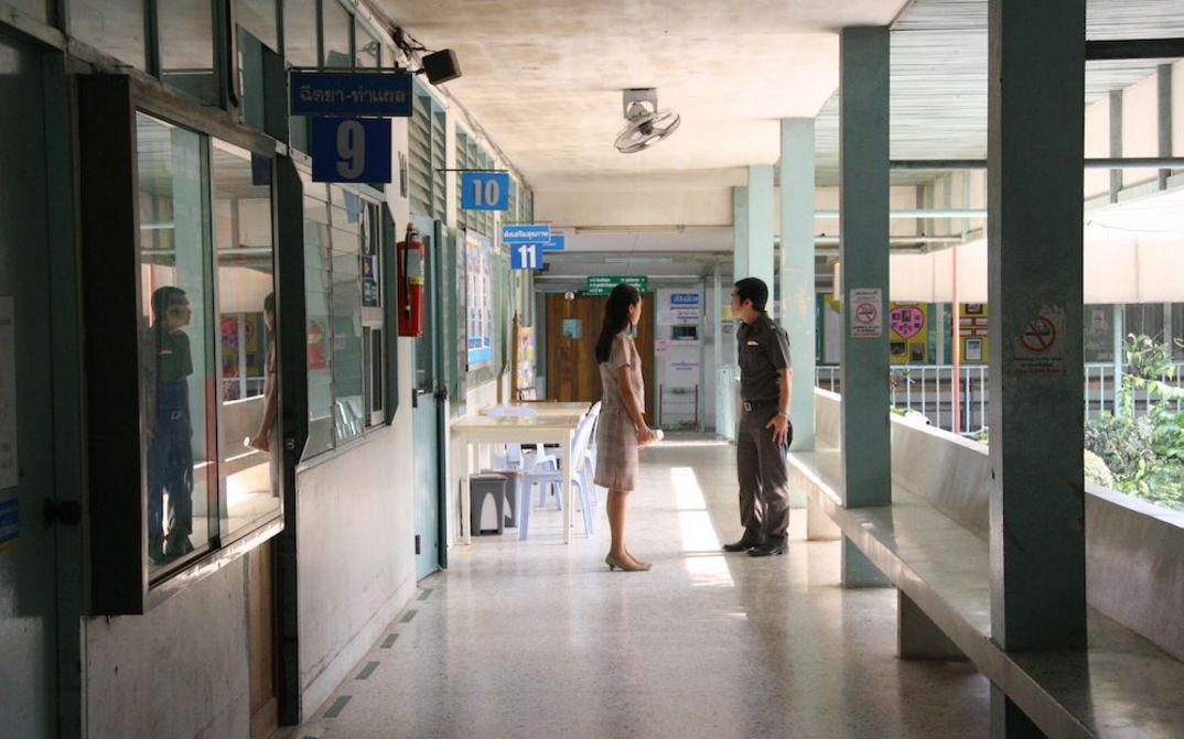 Film still from SYNDROMES AND A CENTURY: A woman and a man are standing in the hallway of a hospital.