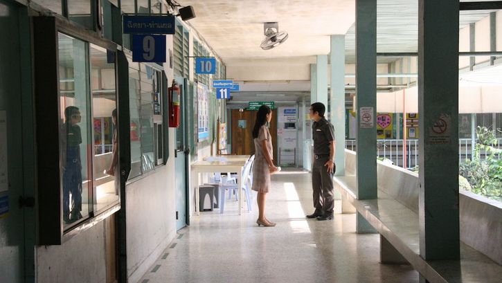 Film still from SYNDROMES AND A CENTURY: A woman and a man are standing in the hallway of a hospital.