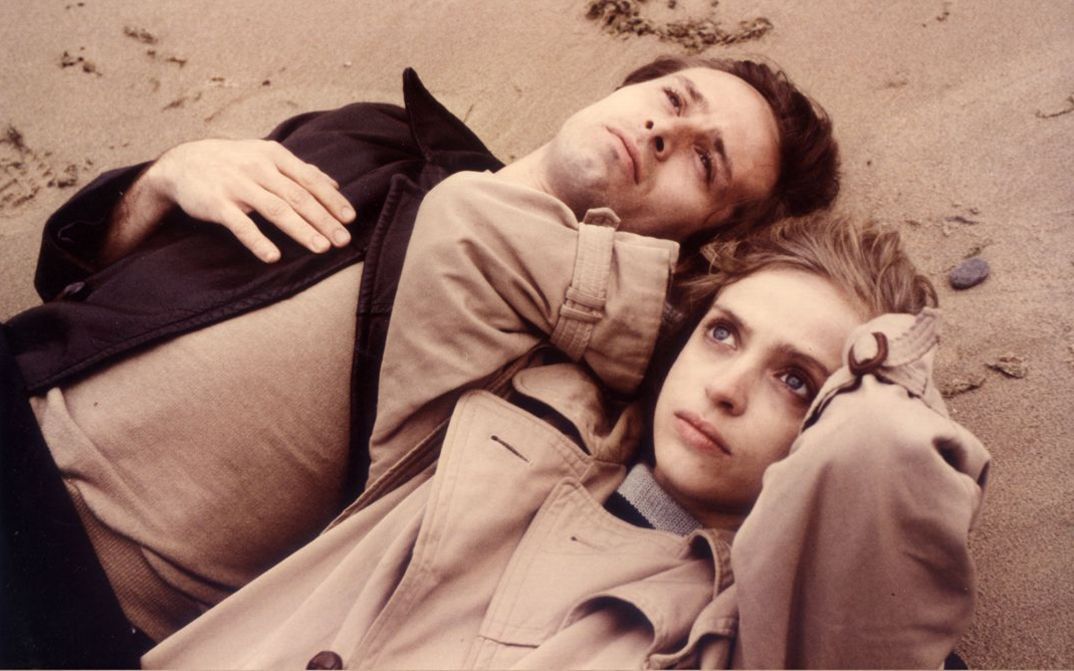 Filmstill aus FLUCHT IN DEN NORDEN. Ein Mann und eine Frauen liegen im Sand und blicken in den Himmel.