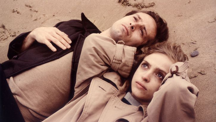 Film still from FLUCHT IN DEN NORDEN. A man and a woman lie in the sand and look up to the sky.