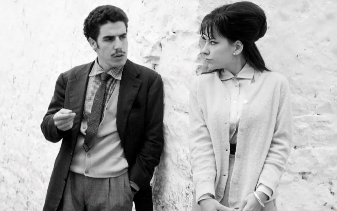 Filmstill aus I BASILISCHI: Ein Mann und eine Frau schauen sich an eine Wand gelehnt an.