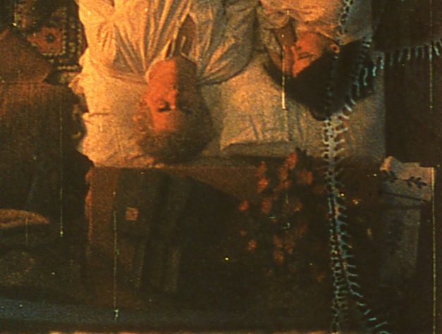 Film still from TO LAVOISIER, WHO DIED IN THE REIGN OF TERROR: Top view of a couple lying in bed. The film material has clearly been altered and shows streaks and stains.
