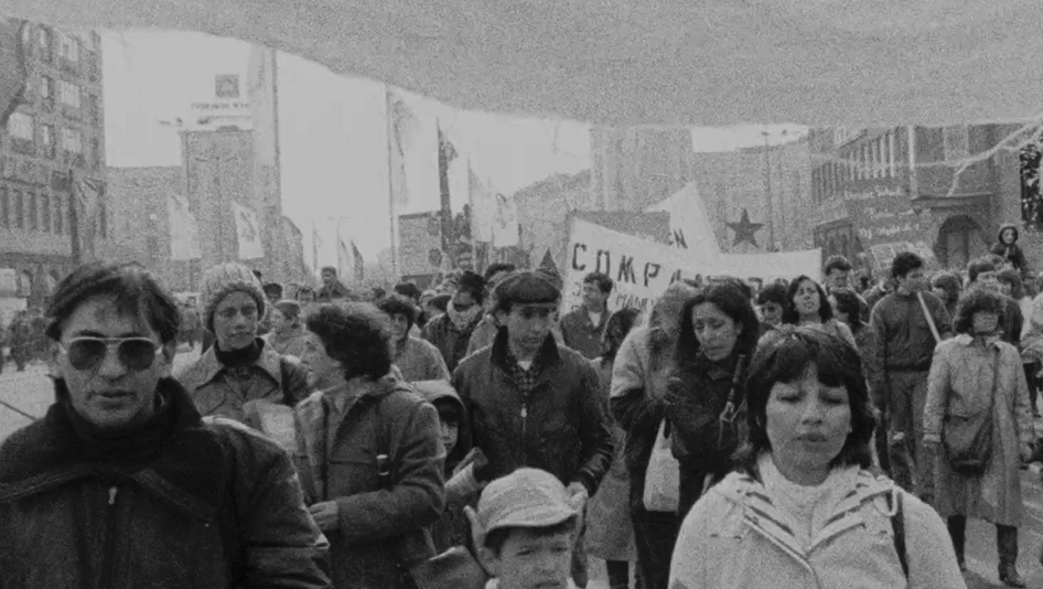 Film still from EXIL: You see people on a demonstration, in the background some banners.