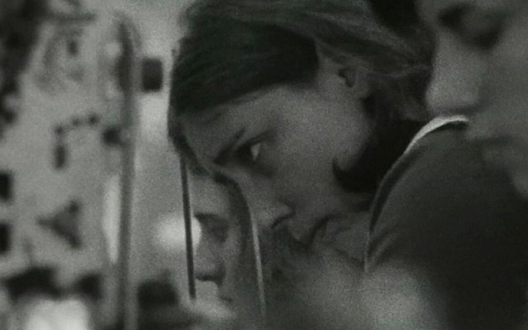 Film still from ES KOMT DRAUF AN, SIE ZU VERÄNDERN: You can see the heads of some young women; they work in a factory.