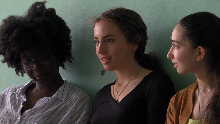 Filmstill aus PREMIÈRES SOLITUDES: Drei Teenager-Mädchen vor einer grün gestrichenen Wand.