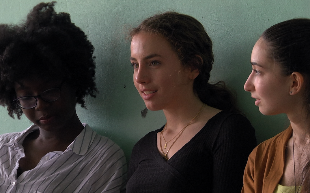 Filmstill aus PREMIÈRES SOLITUDES: Drei Teenager-Mädchen vor einer grün gestrichenen Wand.