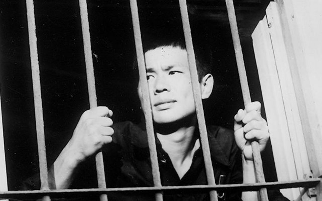 Filmstill aus BAD BOYS: Ein junger Mann klammert sich an die Stäbe eines vergitterten Fensters.
