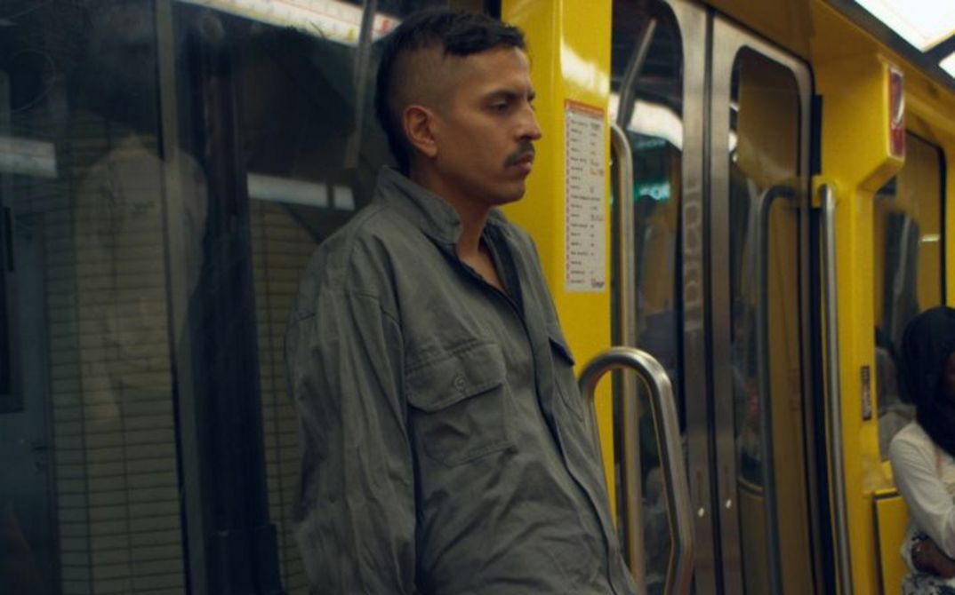 Mann steht in gelbem U-Bahn-Wagen, andere Fahrgäste sitzen im Hintergrund.